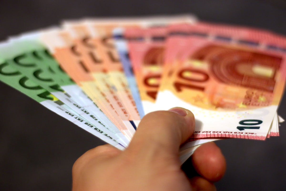 a hand holding a fan of money